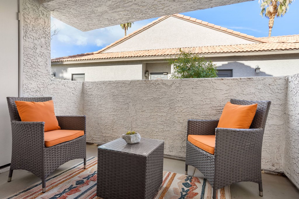 a patio with two chairs and a table with a potted plant on it